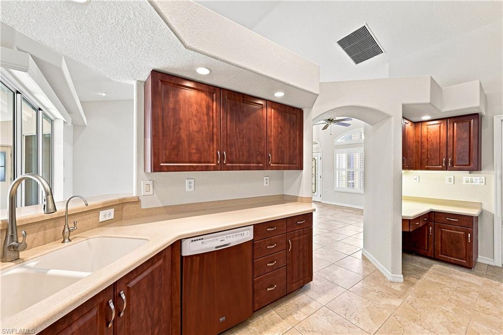 Gourmet kitchen featuring rich wood cabinetry with ample storage, light-filled countertops with undermount sink and professional-grade faucet, recessed lighting throughout, and a spacious island with seating