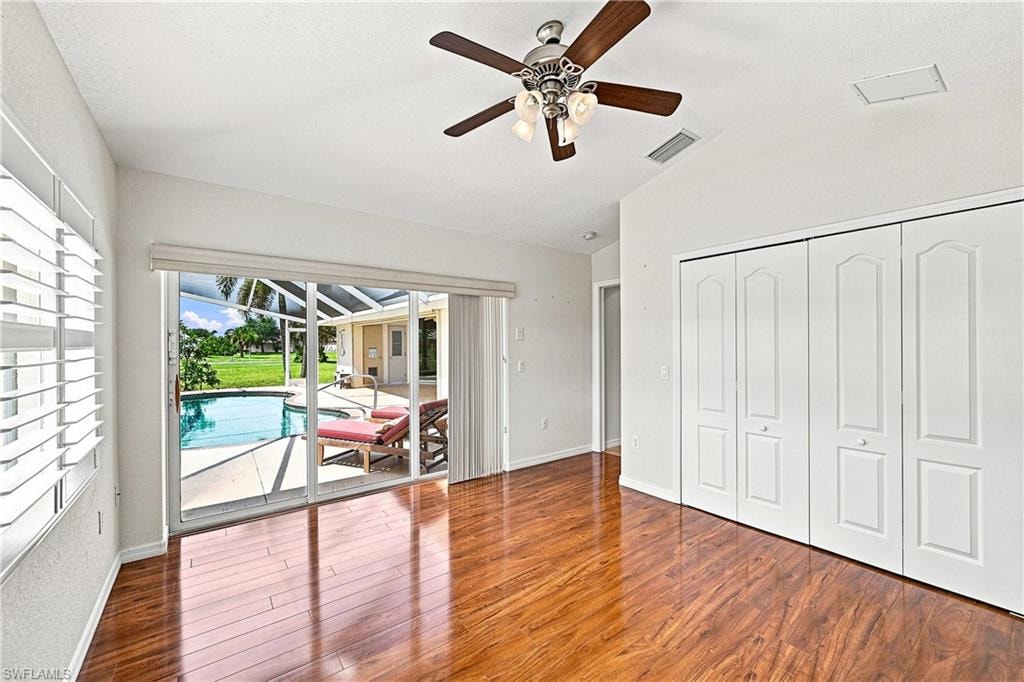 Guest bedroom featuring double closets, wood style flooring and sliding doors to the pool area