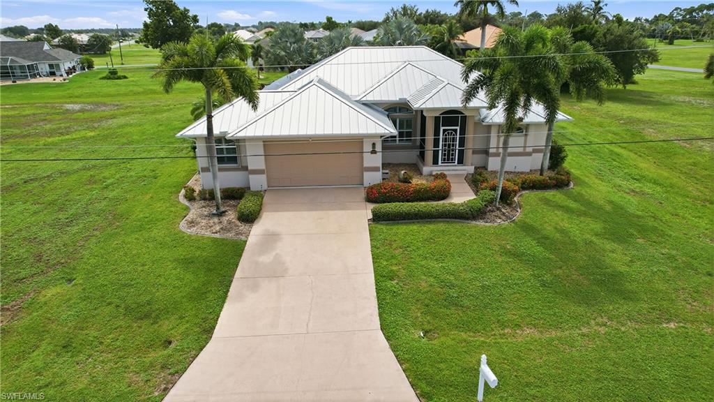 Modern single-story residence showcasing a metal roof with clean architectural lines, flanked by mature palm trees and professional landscaping