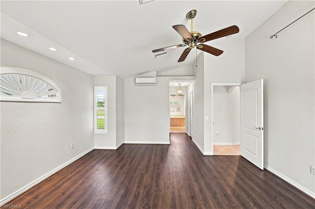 Spacious interior featuring wood-finish flooring, vaulted ceiling, separate supplementary AC unit, hall with dual walk-in closets leading to primary bathroom