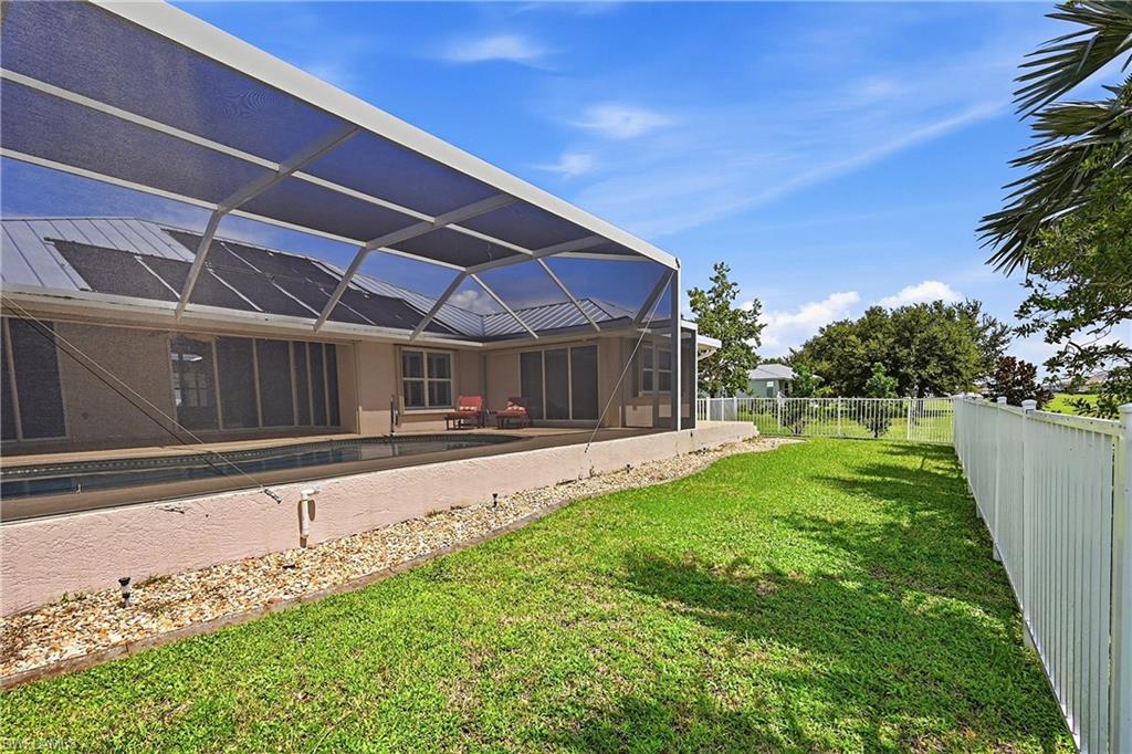 Spacious covered lanai with panoramic screens overlooking expansive manicured lawn and greenspace behind.