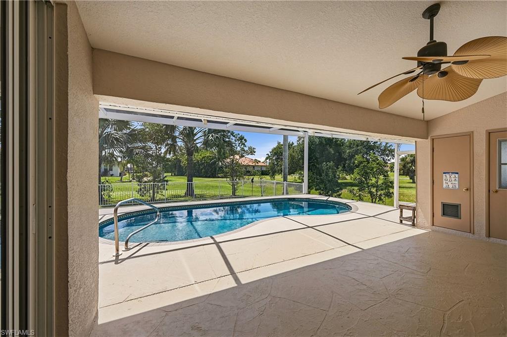 Expansive screened lanai featuring a freeform pool, concrete decking, and a ceiling fan