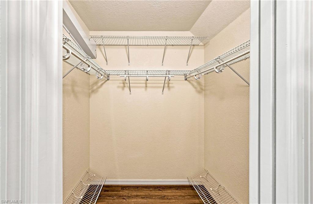 Walk-in closet featuring full wire shelving, hanging rods, wood-finish flooring, and light neutral wall tones