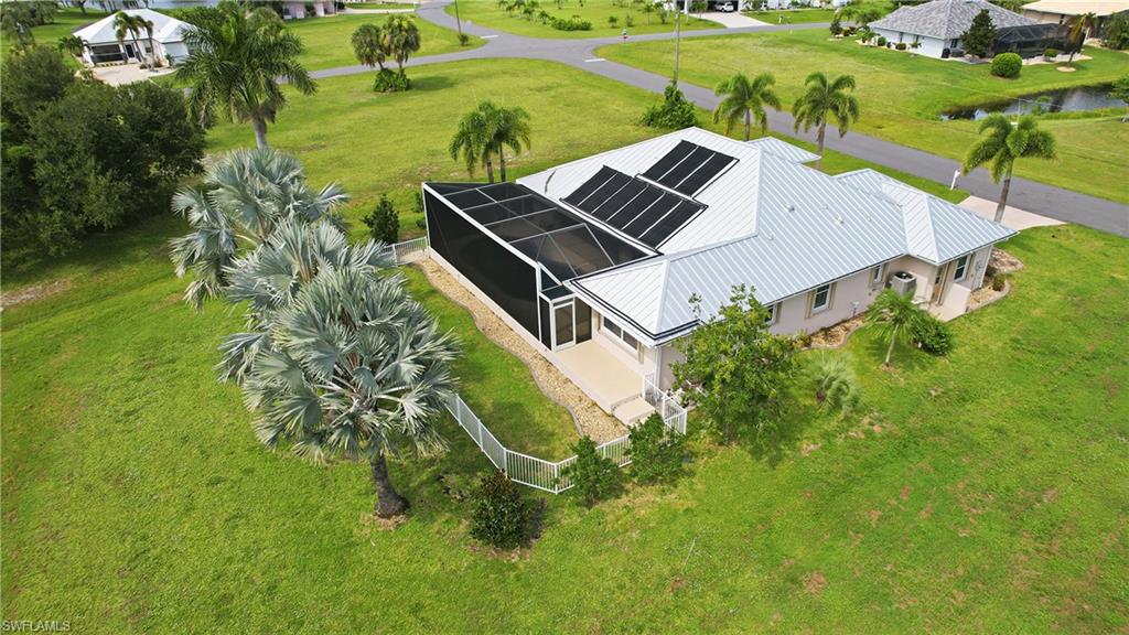 Modern residence featuring a striking silver metal roof with pool solar panel array, positioned on expansive manicured grounds