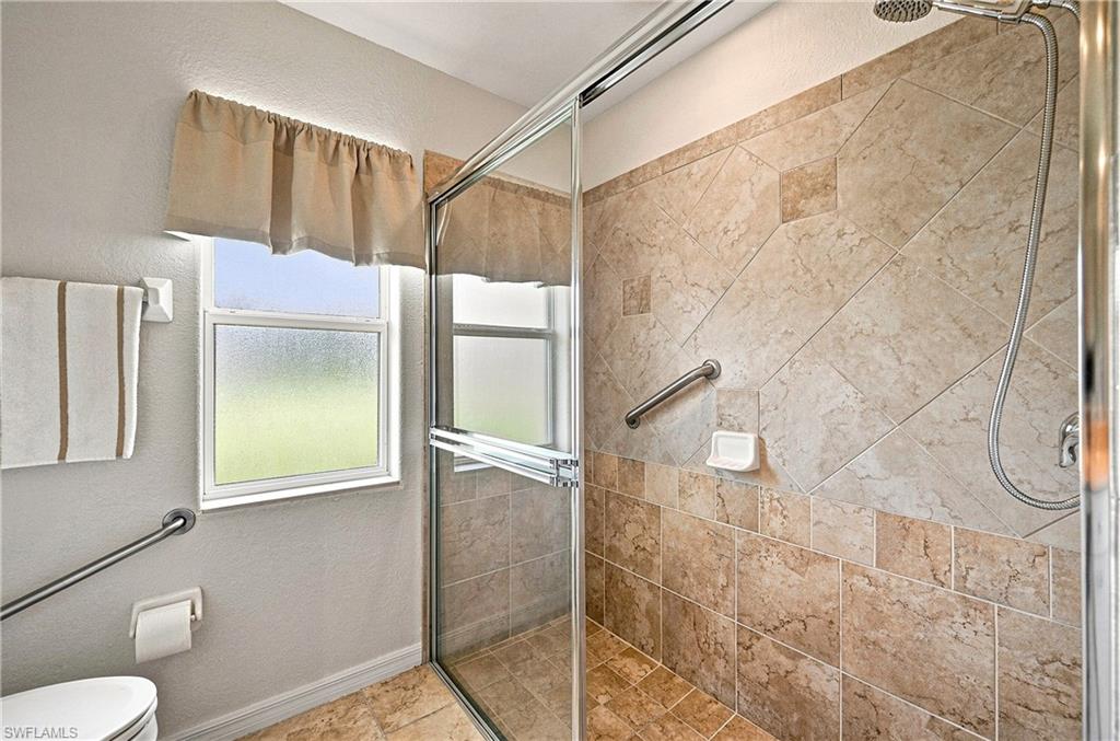 Spa-inspired guest bathroom featuring a walk-in shower with glass enclosure, detachable showerhead, and tile surround