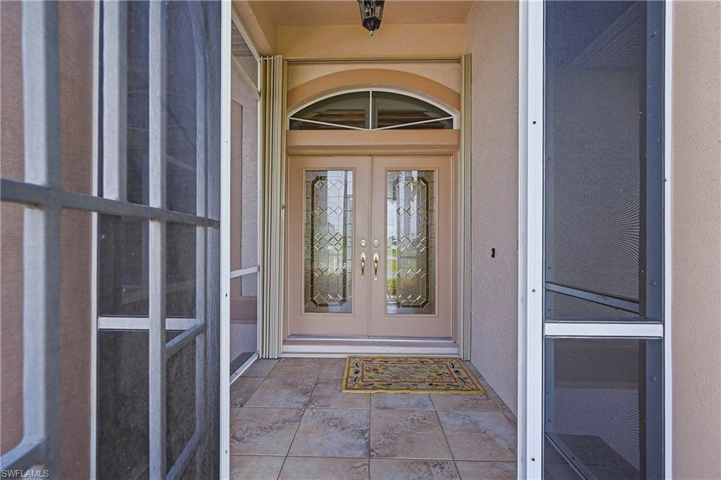 Double entry doors with decorative glass panels and an arched transom window