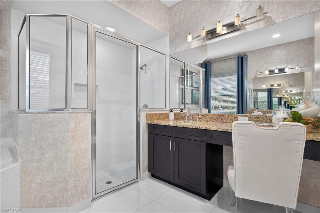 Walk-in shower with clear glass enclosure and white tile surround