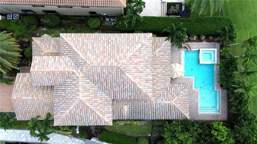 Tile roof with multiple gables, rectangular swimming pool, integrated spa, and manicured landscaping