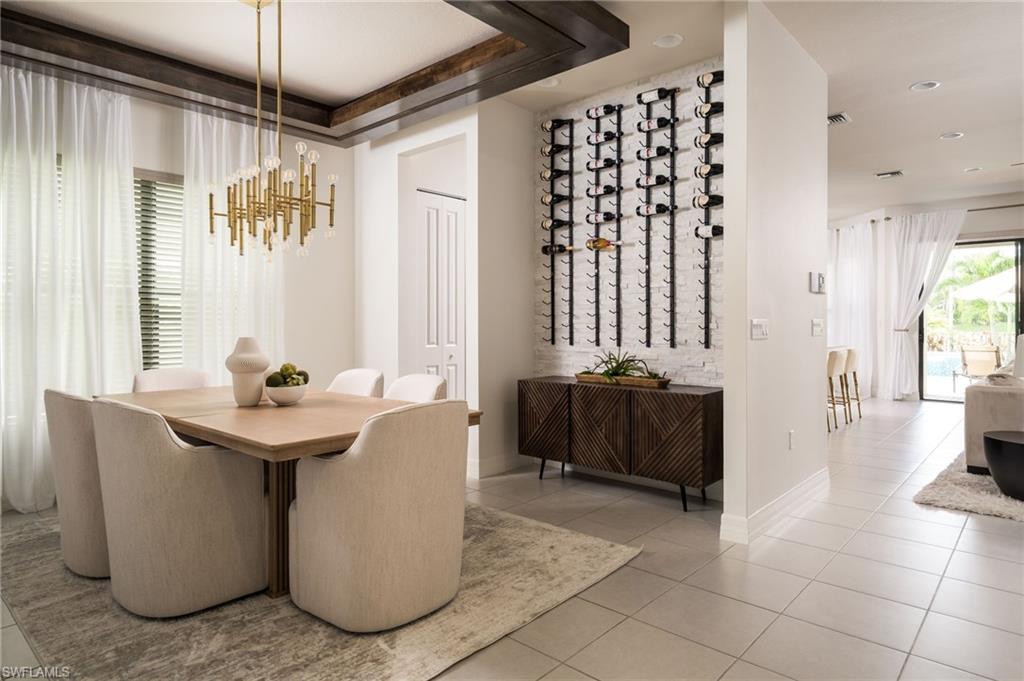 Dining area featuring a textured wine wall, contemporary chandelier, wood-finish beam accents, and tile flooring