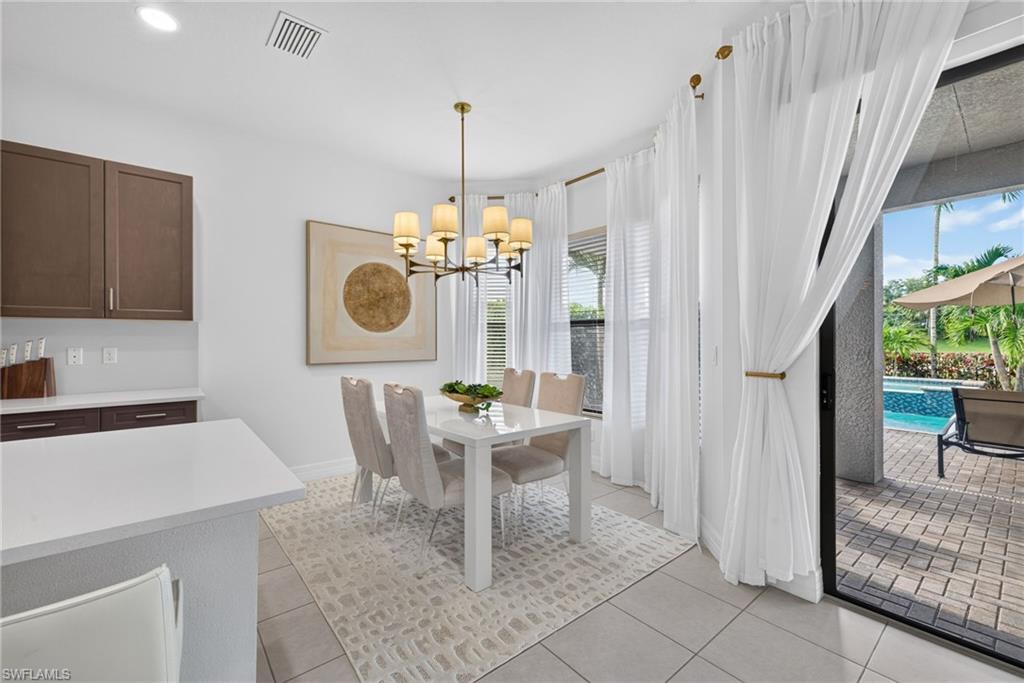 Bright dining area featuring a contemporary chandelier, large windows with privacy blinds, and light tile flooring