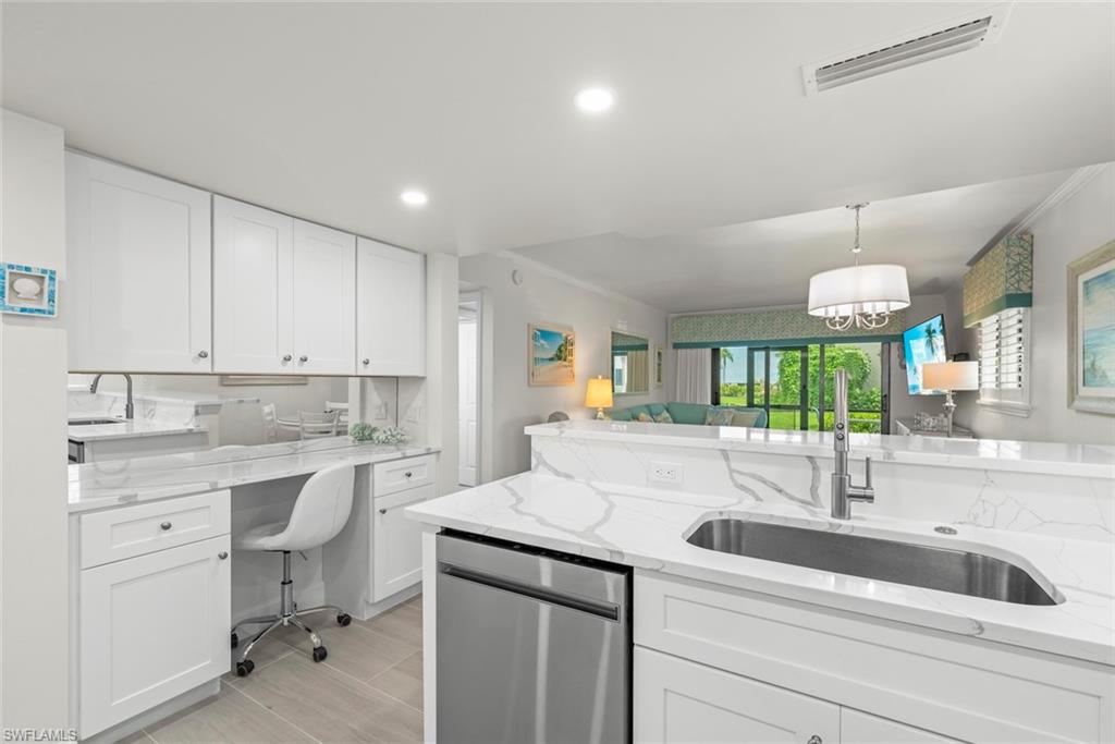 Kitchen featuring white cabinetry, quartz countertops, an undermount stainless steel sink with a modern faucet, and integrated stainless steel appliances