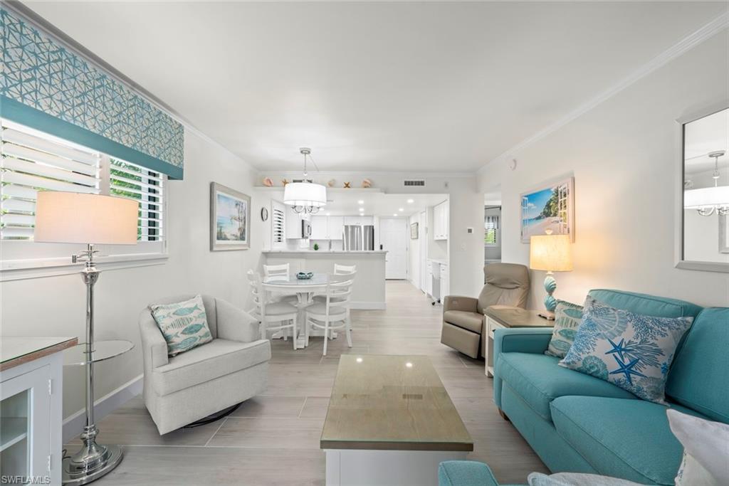 Open-concept living space featuring wood-finish flooring, plantation shutters, and crown molding