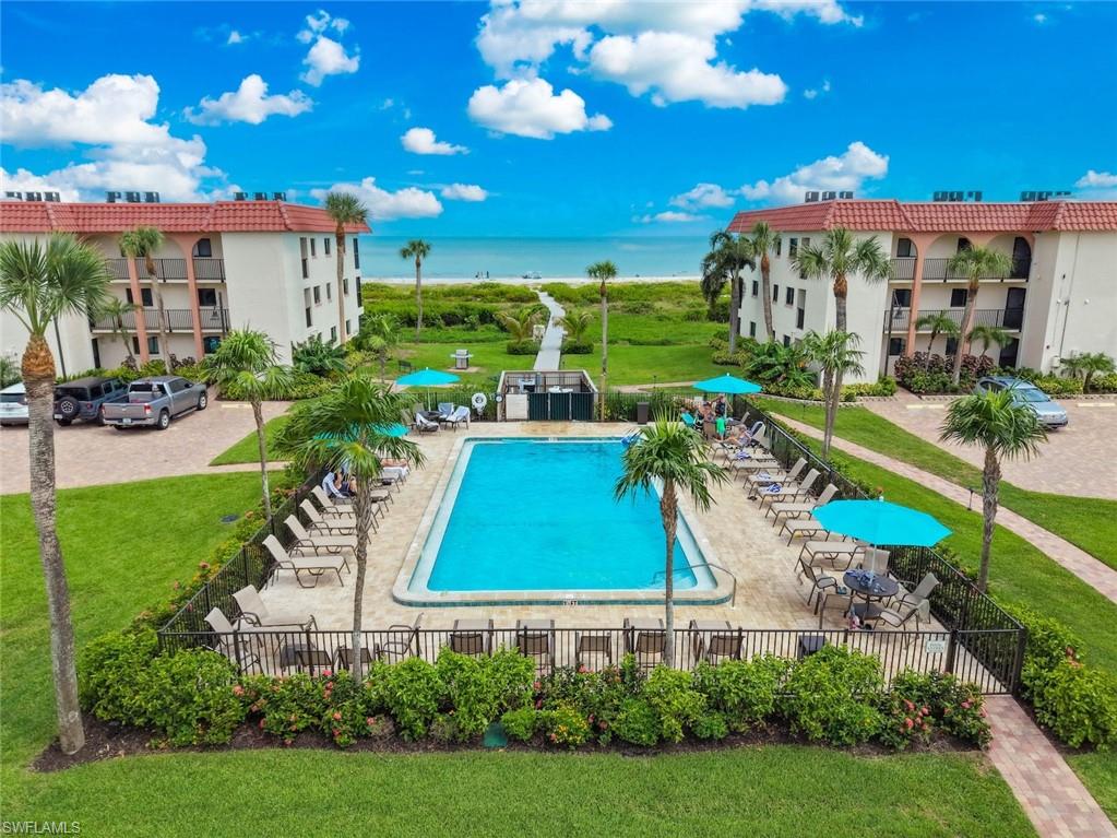 Resort-style pool area featuring a rectangular swimming pool, surrounding patio with lounge seating, and a privacy fence