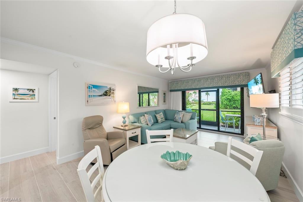Open-concept living area featuring light wood-finish flooring, a contemporary drum chandelier, and a sliding glass door leading to an outdoor space