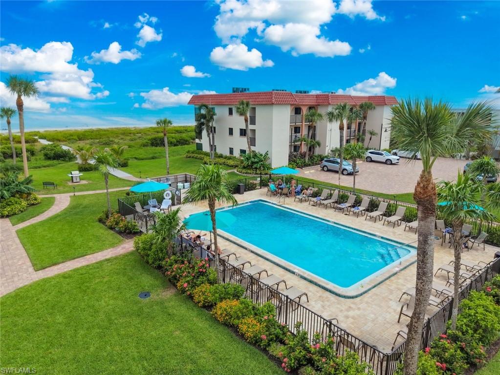 Resort-style outdoor pool area featuring a rectangular pool, paver deck, and surrounding lounge seating
