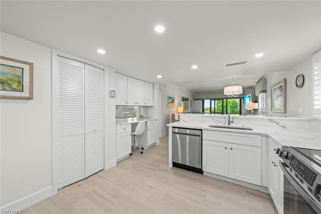 Modern kitchen featuring white cabinetry, light-toned wood-finish flooring, and a stainless steel dishwasher