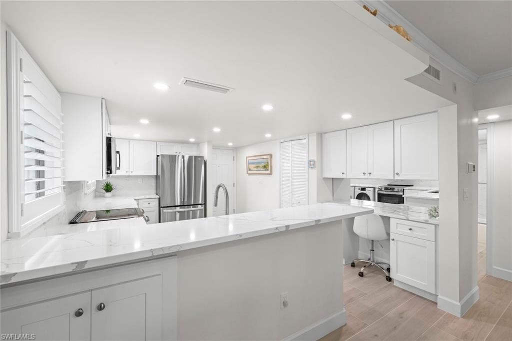 Modern kitchen featuring white cabinetry, integrated stainless steel appliances, and quartz countertops with a waterfall edge