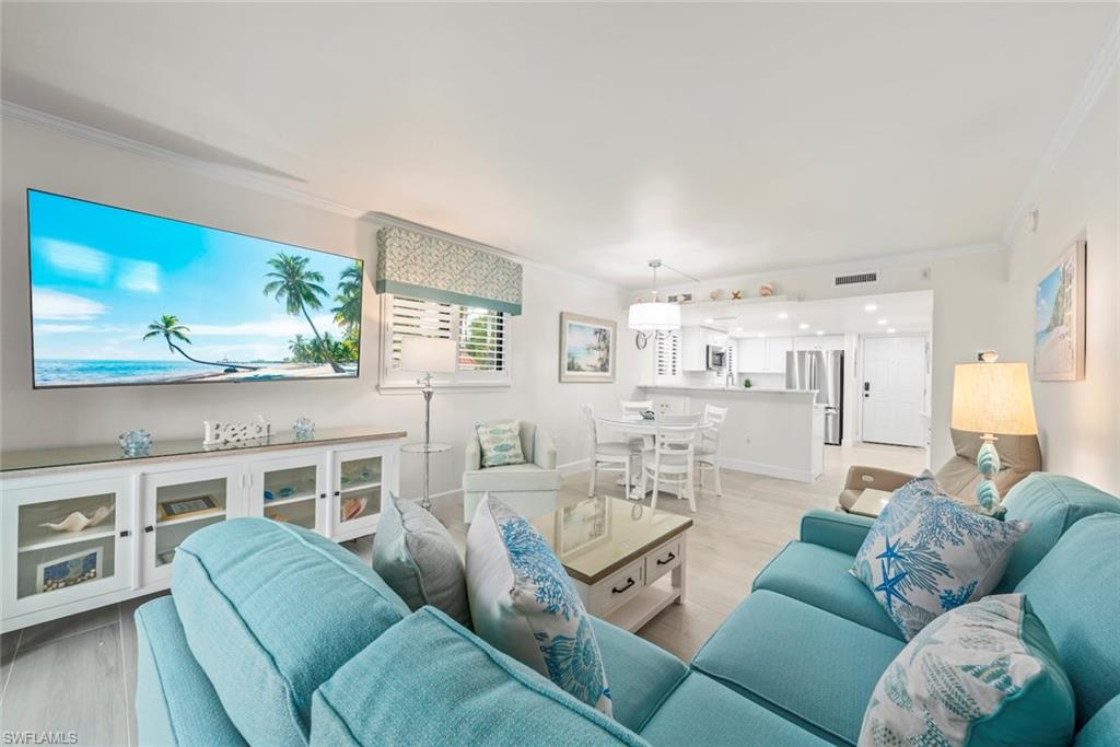 Open-concept living space featuring light wood-finish flooring, white crown molding, and recessed lighting