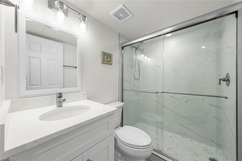 Contemporary bathroom featuring a spacious glass-enclosed shower with subway tile surround, a white vanity with an integrated sink, polished chrome faucet, and a large mirror with overhead lighting
