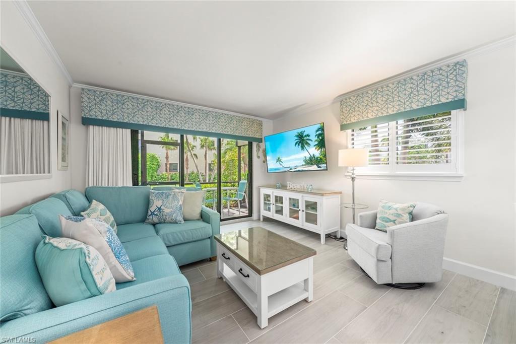Living area featuring wood-finish flooring, crown molding, and a large glass sliding door leading to an outdoor space
