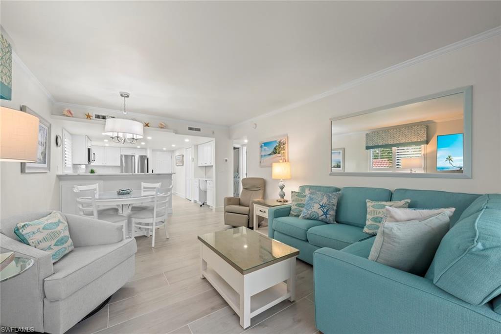 Open-concept living area featuring light-toned flooring, crown molding, and recessed lighting