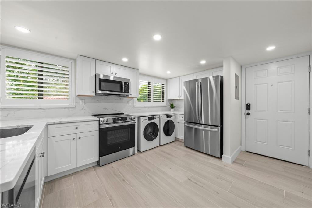 Modern kitchen featuring white cabinetry, quartz countertops with a matching backsplash, stainless steel appliances, and integrated laundry machines