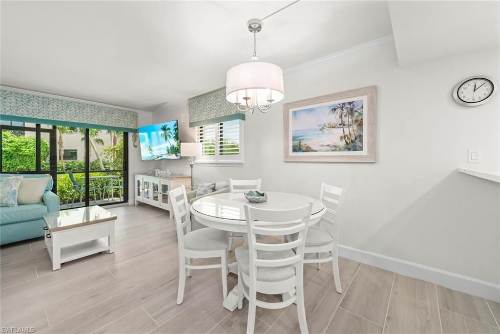Open-concept living and dining area featuring wood-finish flooring, a contemporary chandelier, and a large sliding glass door