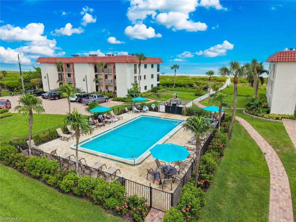 Outdoor swimming pool with a paved deck, surrounded by mature landscaping and a black metal fence