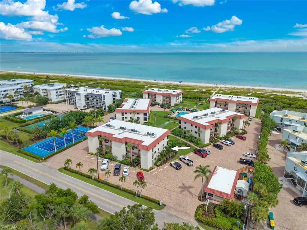 Coastal condominium complex featuring multiple buildings, direct beach access, tennis courts, and swimming pools