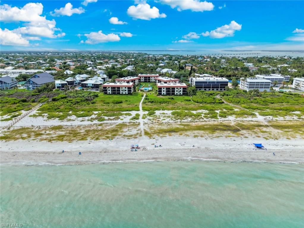 Coastal property featuring direct beach access, multiple residential buildings, and a lush green landscape