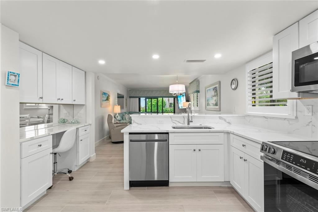 Open-concept kitchen featuring white shaker cabinetry, stainless steel appliances, and light-toned tile flooring
