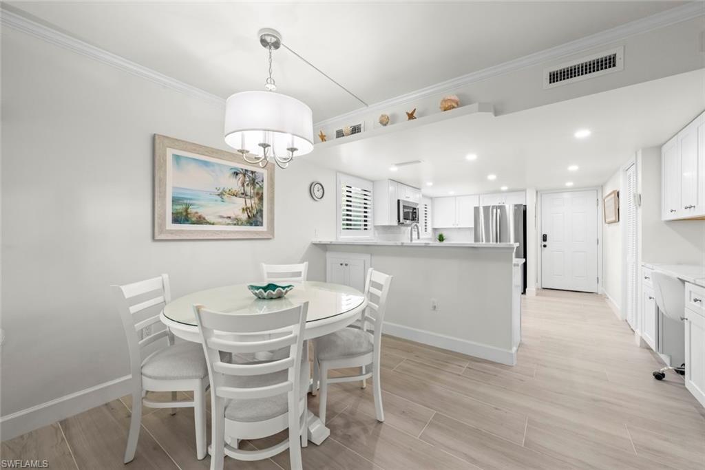 Open-concept dining and kitchen area with light wood-finish flooring, recessed lighting, and a white kitchen island