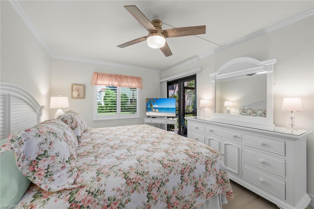 Bedroom featuring a ceiling fan with light fixture, crown molding, and plantation shutters