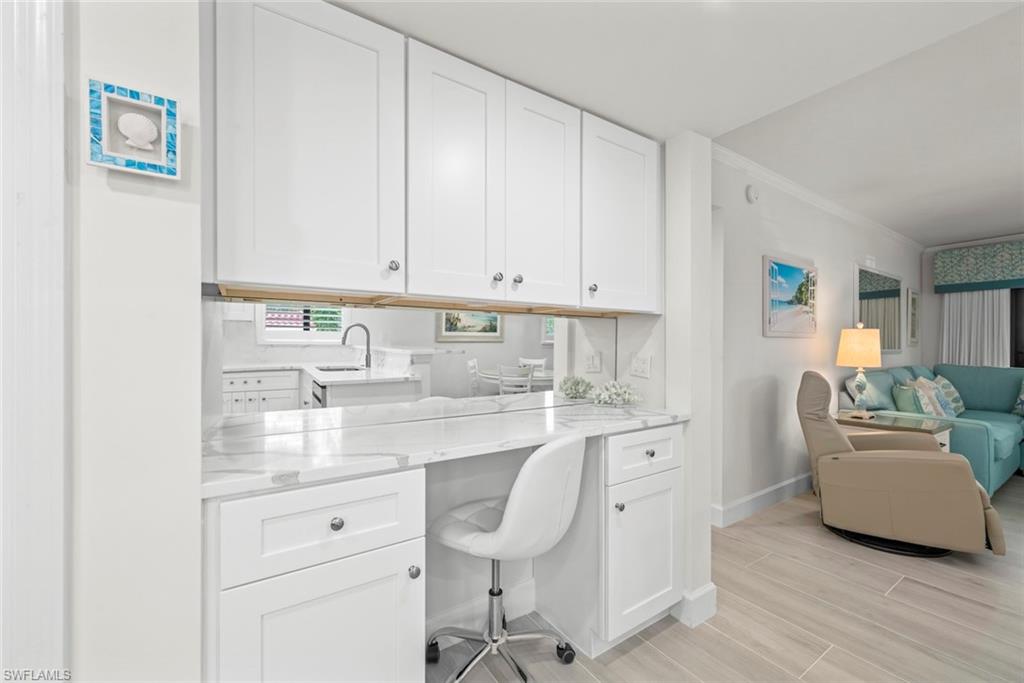 Built-in desk area featuring white cabinetry, a light-toned countertop, and a mirrored backsplash