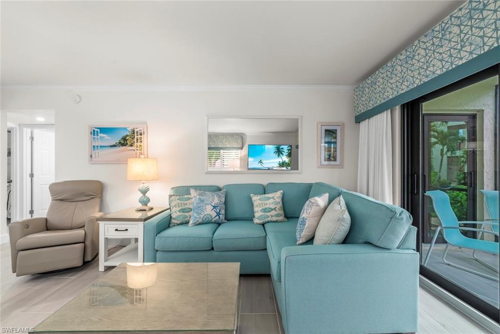 Living area featuring wood-finish flooring, a bright paint palette, and crown molding