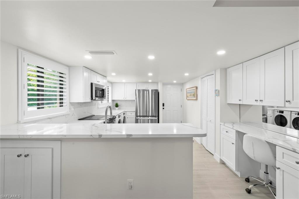 Modern kitchen featuring white shaker cabinetry, stainless steel appliances, marble-look countertops, and recessed lighting