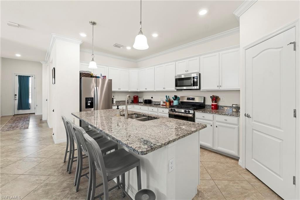 Eat-in kitchen island seats four, featuring granite countertops, stainless steel appliances, a gas range, and a walk-in pantry.
