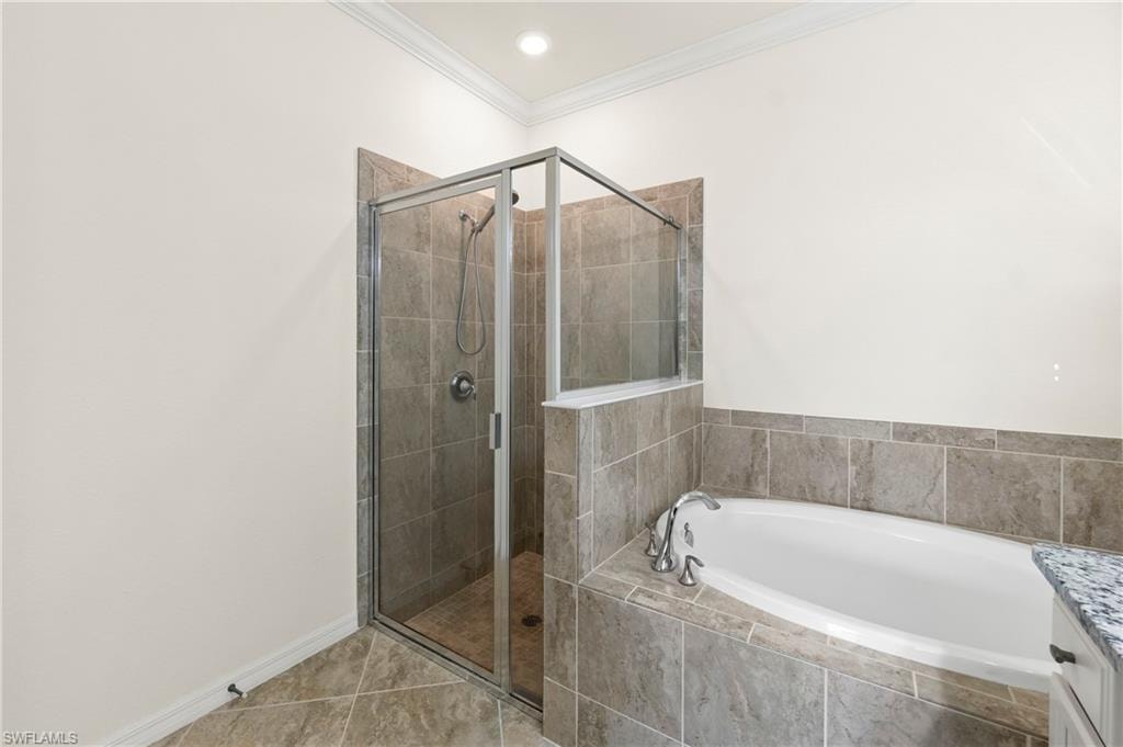 Bathroom featuring a glass-enclosed shower, built-in soaking tub, tiled floor, crown molding, and granite countertop
