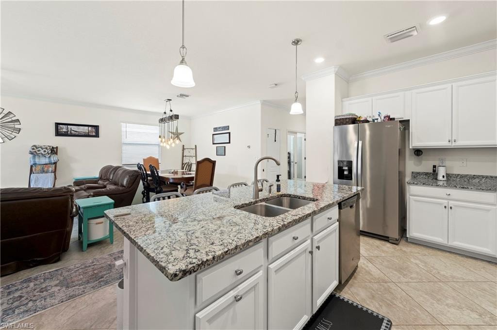 Kitchen island with granite countertops and bar seating, stainless steel gas range, white shaker-style cabinetry, and a walk-in pantry. Tile flooring throughout.