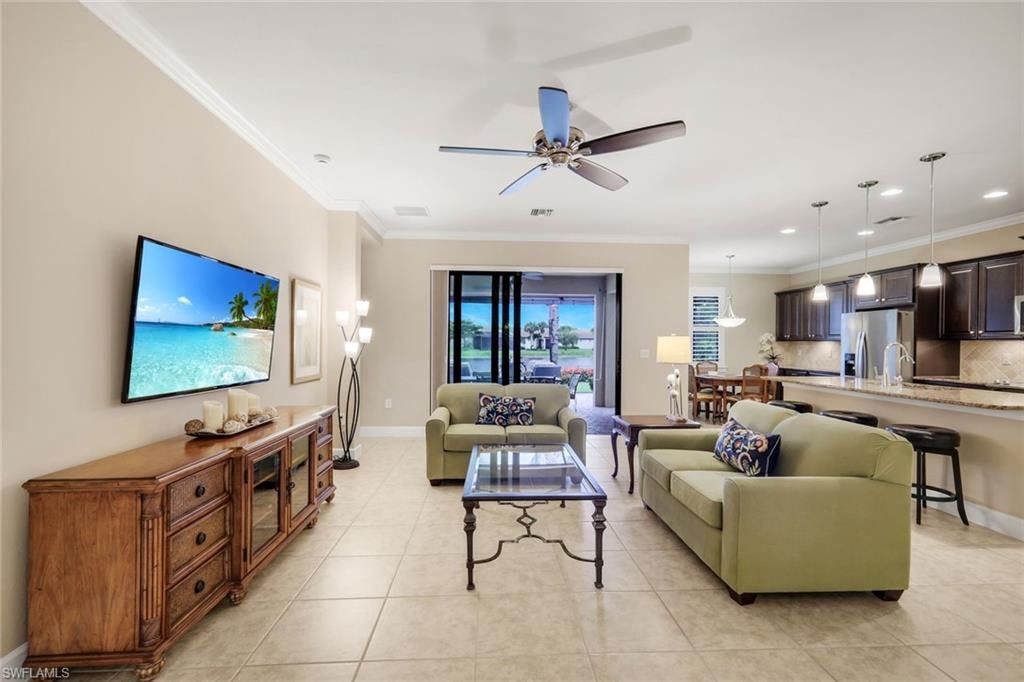 Open concept living area with tiled flooring, crown molding, and a ceiling fan