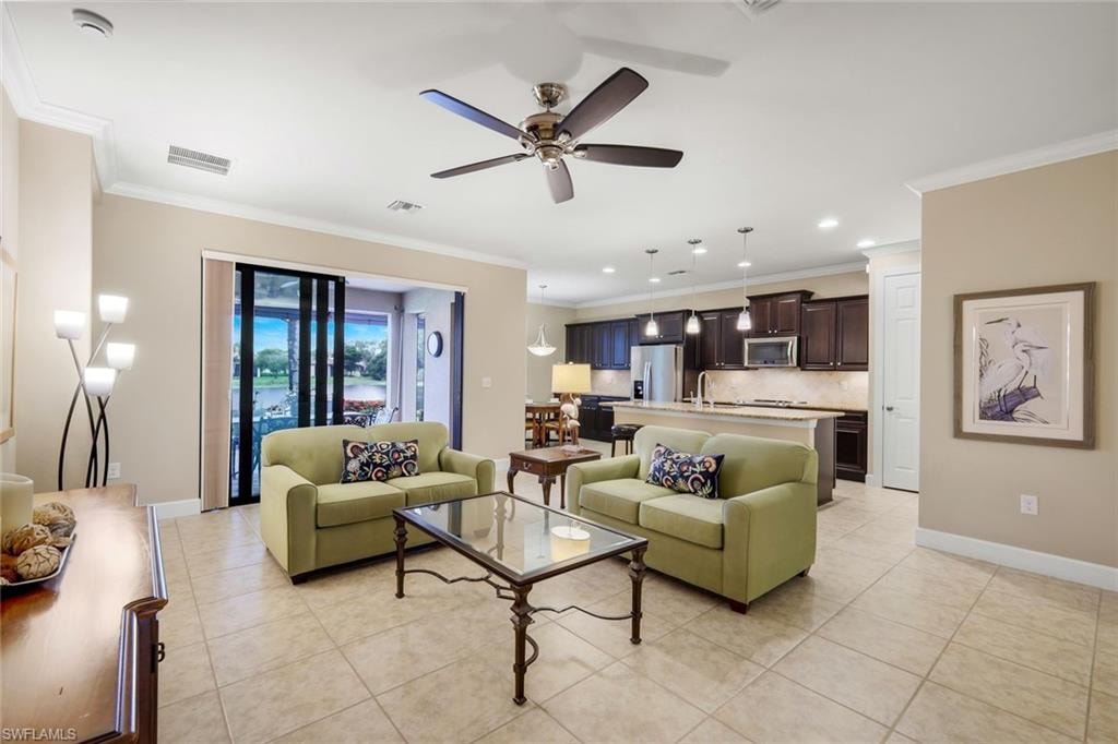 Spacious open-concept living area with tile flooring, a ceiling fan, and crown molding