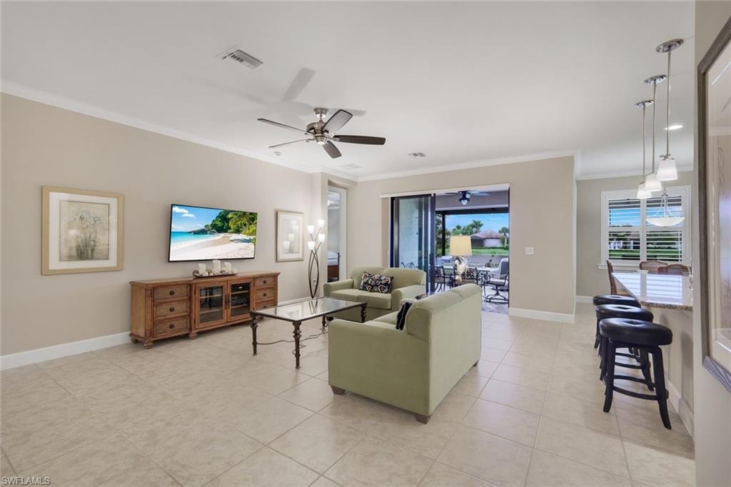 Open-concept living space featuring tile flooring, crown molding, and a ceiling fan