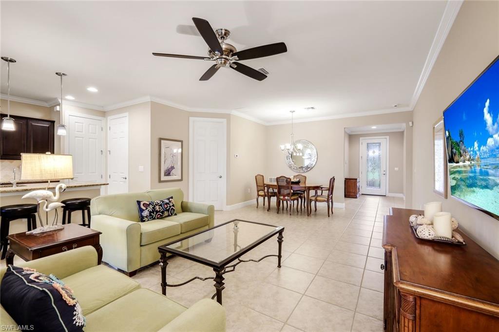 Open-concept living space with tiled flooring, crown molding, and a ceiling fan
