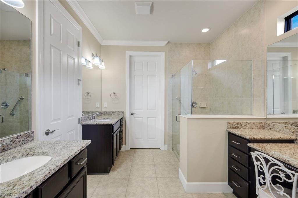 Dual vanity sinks, separate walk-in shower with glass enclosure, granite countertops, recessed lighting, and tile flooring