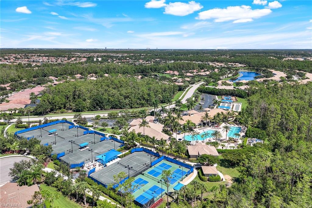Aerial view of community amenities, including multiple tennis courts, a large swimming pool with surrounding lounge areas, and a clubhouse structure