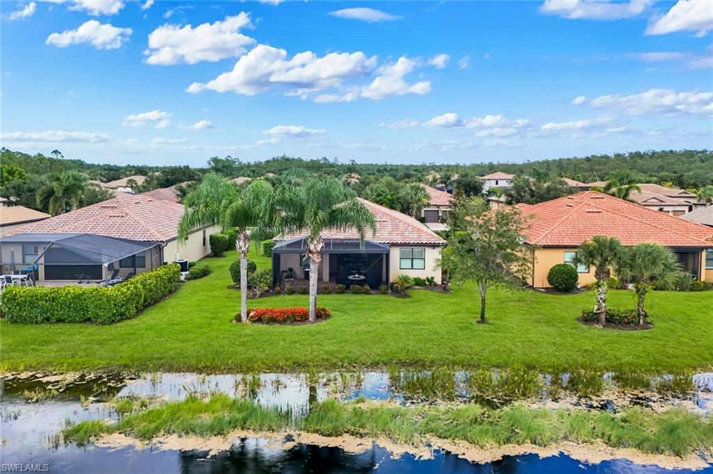 Expansive green lawn with mature landscaping, screened enclosure, and waterside frontage