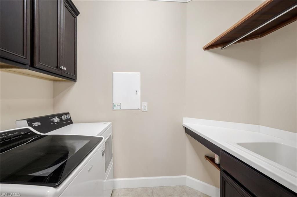 Laundry area featuring dark wood-finish cabinetry, white countertop, and a built-in sink