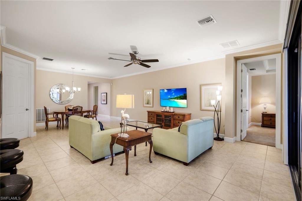 Open-concept living space featuring tile flooring, a ceiling fan, and crown molding
