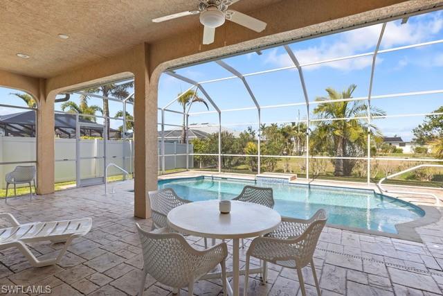Expansive screened lanai featuring a resort-style heated swimming pool with spa jets, complemented by a round dining table with seating for four