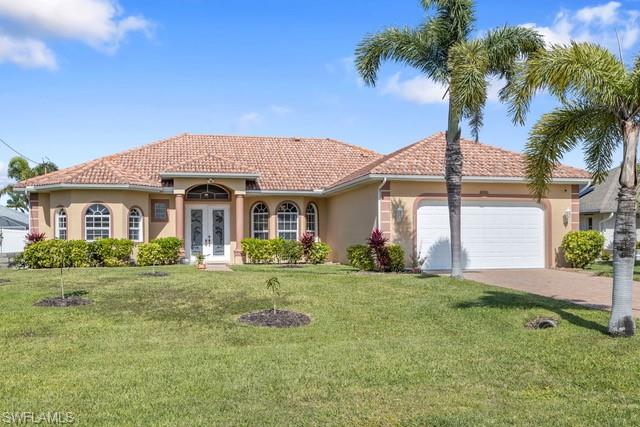 Stucco exterior featuring a terracotta tile roof, arched windows, and a double-door entry with decorative glass